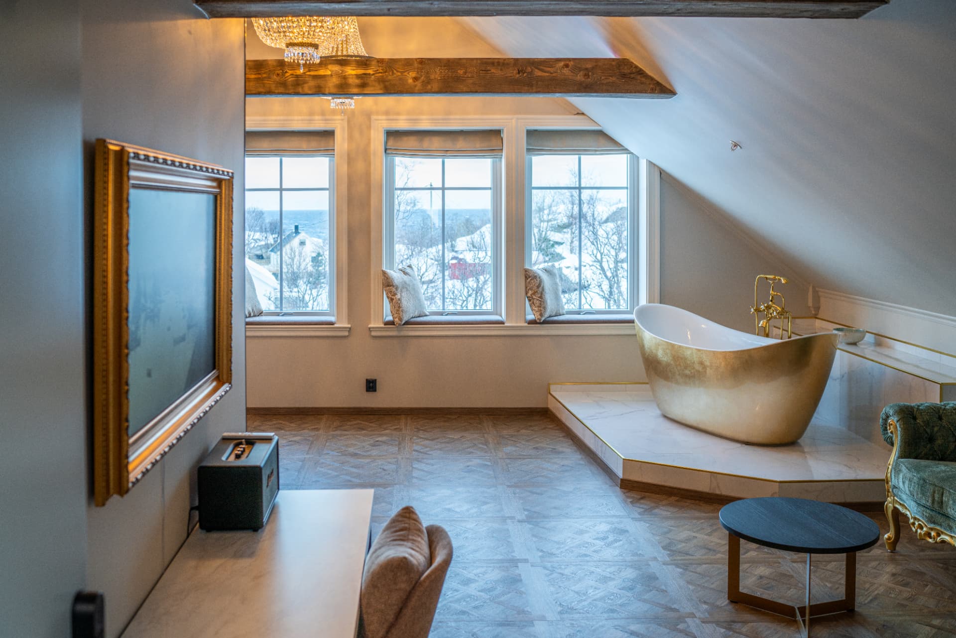 URE suite — gold freestanding bath beside three windows looking out on winter Lofoten