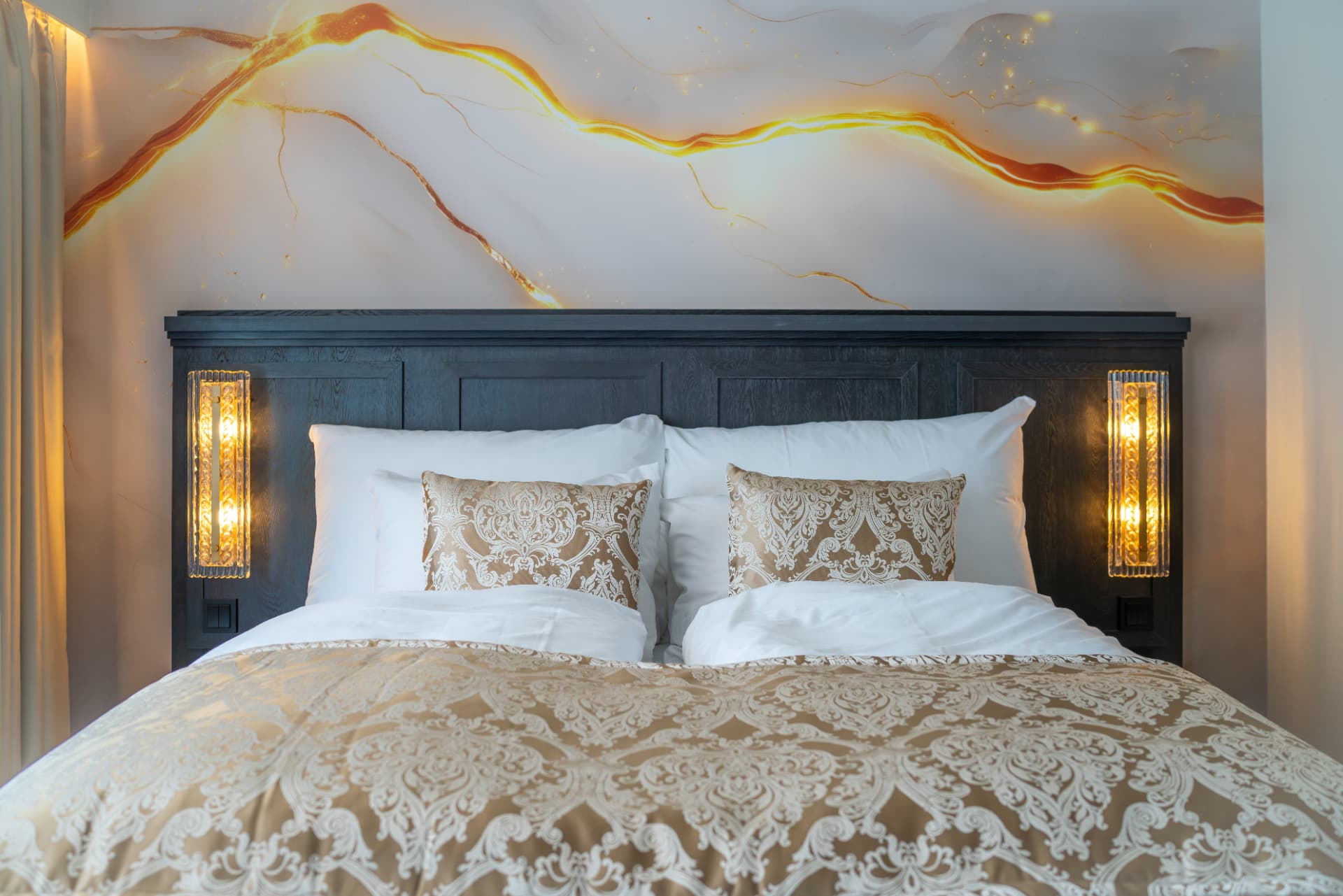 URE suite — dark oak headboard, crystal sconces and a hand-painted amber mural
