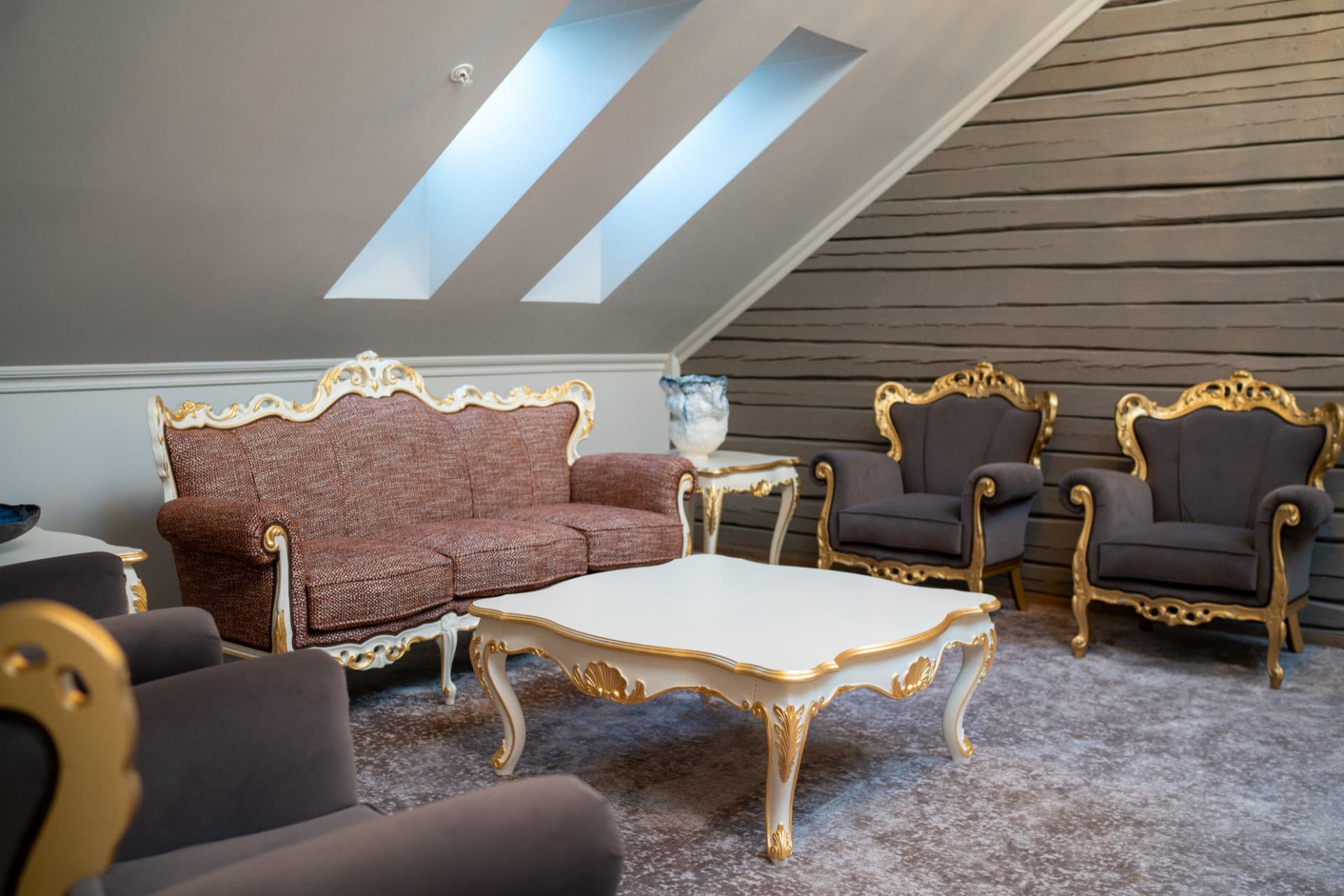 URE lounge — gilded baroque seating under skylights and aged timber walls